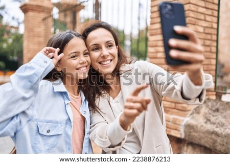 Woman and girl mother and daughter making selfie by the smartphone at street