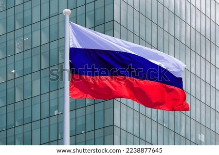Waving in the wind flag Russia on background of a modern building. Concept of politics, business and tourism in Russia