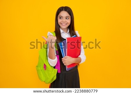 Schoolchild, teenage student girl with school bag backpack hold book on yellow isolated studio background. Children school and education concept. Royalty-Free Stock Photo #2238880779