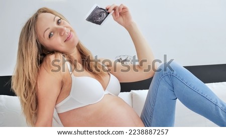 Ultrasound image pregnant baby photo. Woman holding ultrasound pregnancy picture. Pregnancy, medicine, pharmaceutics, health care and people concept.