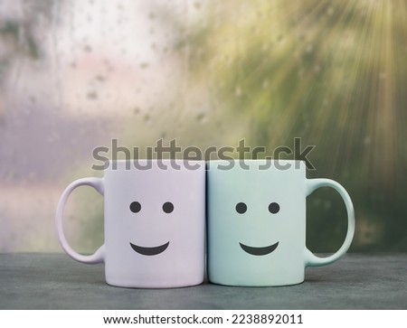 Happy, similing face, mug couple on a window sill cuddle, cup of coffee on a rainy day, support, relationship and friendship concept  Royalty-Free Stock Photo #2238892011