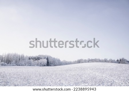 Winter landscape with snow covered hills and a forest in the background