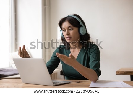 Engaged online teacher, coach giving workshop, webinar, using laptop, wireless headphones, recording podcast. Business woman, freelance employee talking on video call, working from home Royalty-Free Stock Photo #2238906641