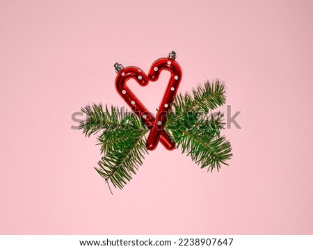 Christmas composition. Heart made of red Christmas lollypops with pine tree branches on pink table background. Flat lay, top view, copy space. Happy New Year card. Pink Christmas. Heart shaped, love.