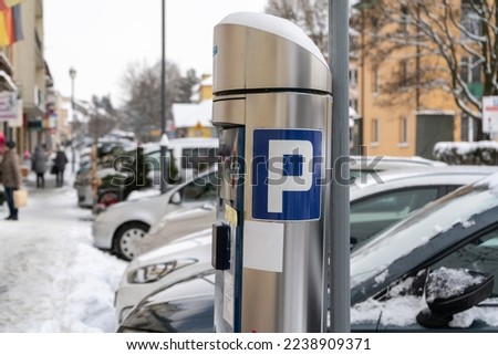 Parking meter (Parkometr or Parkomat) in a paid car park zone. Covered in snow on a cold winter day in Poland. Royalty-Free Stock Photo #2238909371
