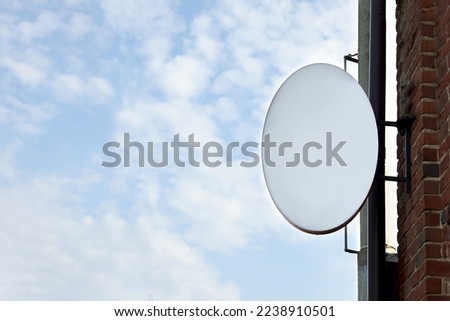 Advertising board on building wall against blue sky, space for text