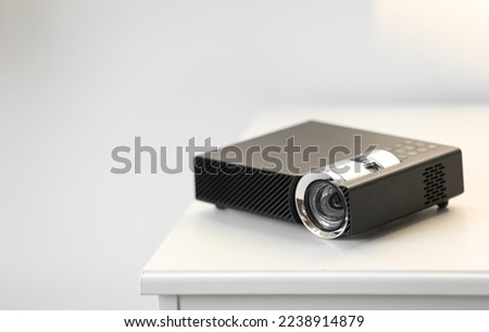 Modern video projector on white table indoors. Space for text
