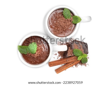 Cups of delicious hot chocolate with mint and cinnamon sticks on white background, top view