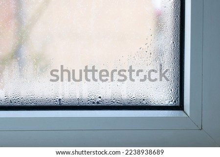 Close up of double glazed window  condensation causes by excessive moisture in the house in winter occurs when the seal between panes is broken or desiccant inside the window. Royalty-Free Stock Photo #2238938689