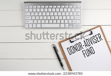 Home office workspace with keyboard, clipboard and pen with text DONOR ADVIDER FUND on white wooden background , business Royalty-Free Stock Photo #2238943785