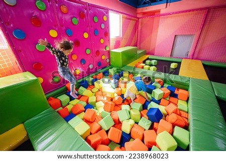Brother with sister playing at indoor play center playground , jumping in color cubes pool. Royalty-Free Stock Photo #2238968023