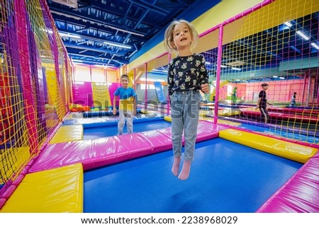 Happy kids playing at indoor play center playground. Girl ljumping on trampoline. Royalty-Free Stock Photo #2238968029