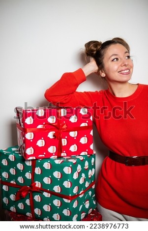 Portrait of young attractive cute brunette girl with bundles in red pullover, smiling happily widely,  enjoying her Christmas green red presents with ribbons