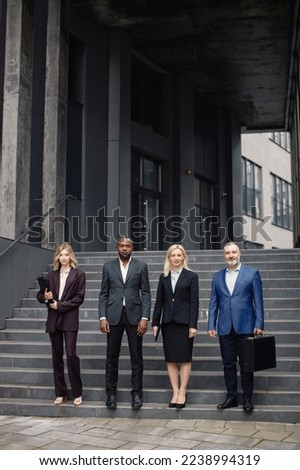 Business people standing in front of modern office and posing for a photo
