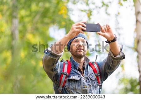 Middle aged hiker taking a photo with his mobile phone. Close up view.