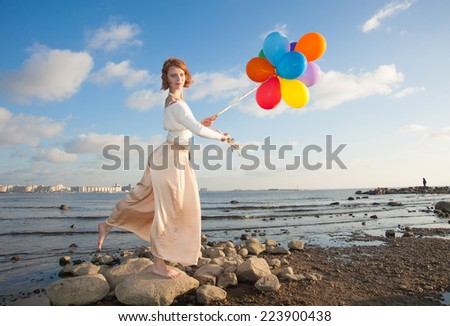 girl with colorful balloons on the beach