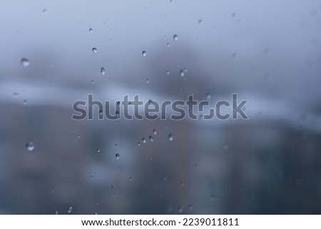 The unhappy scene, foggy glass window with raindrops. Selective focus on the photo. Blurred background with houses. City landscape. Depression and sadness concept.