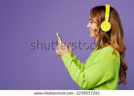 Side view young woman 30s wearing casual green knitted sweater headphones listen to music dance gesticulating hands have fun isolated on plain pastel purple background studio. People lifestyle concept Royalty-Free Stock Photo #2239017261