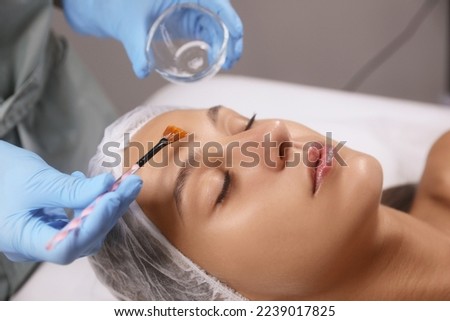 Cosmetologist applying chemical peel product on client's face in salon Royalty-Free Stock Photo #2239017825