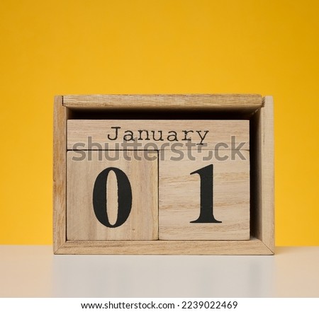 Wooden calendar made of cubes on a yellow background. Date January 1st, beginning of the year