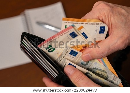Close-up of a man's hands counting money in a purse. Royalty-Free Stock Photo #2239024499