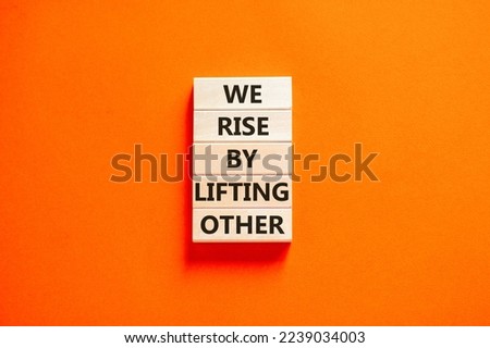 We rise by lifting other symbol. Concept words We rise by lifting other on wooden blocks. Beautiful orange table orange background. Business we rise by lifting other concept. Copy space.