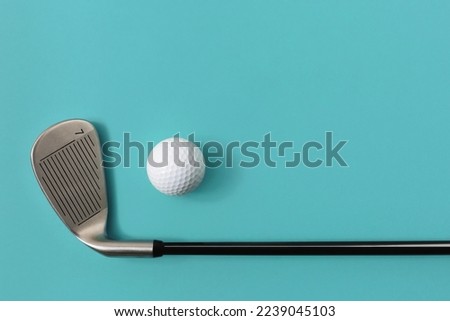 Golf club and golf ball isolated on light turquoise green background. Space for text.