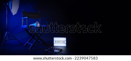Director chair with cinema lightbox sign Director text on it and clapperboard megaphone and black background studio. Director seat on video production or filming set used in film industry. Real no 3D Royalty-Free Stock Photo #2239047583