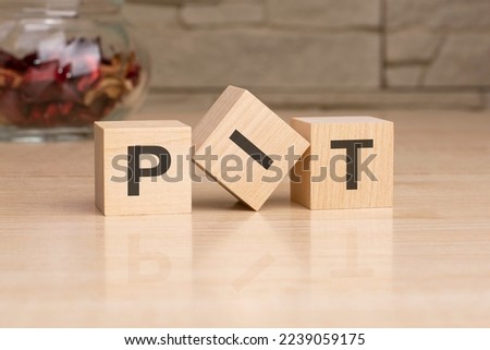 PIT - acronym from wooden blocks with letters, top view on grey background.