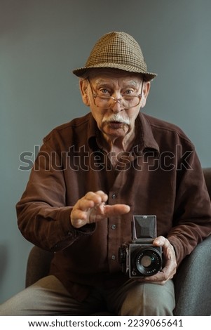 An old photographer with a medium format film camera in his hands.