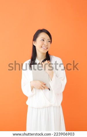 attractive asian woman reading book in the living room on orange background