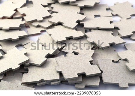 A large pile of gray puzzle pieces. Ready to solve or start. Cardboard. Close up and isolated on a white background.