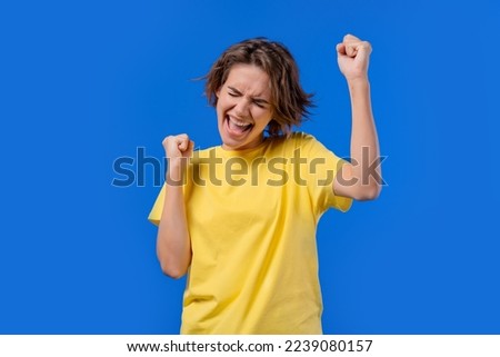 Pretty woman shows triumph yes gesture of victory, she achieved result, goals. Girl glad, happy, surprised excited happy lady on blue background. Jackpot concept. High quality photo