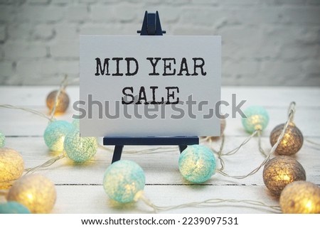 Mid Year Sale text on white brick wall and wooden background