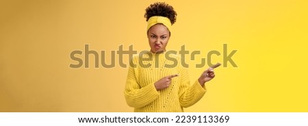 Arrogant peeky young girlfriend behave rude disrespectful frowning wrinkle nose disgust offence pointing left frowning dislike annoyance aversion, express disappointment, standing yellow background. Royalty-Free Stock Photo #2239113369