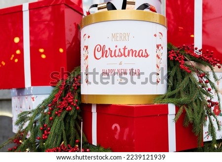 Against the background of a Christmas tree and decorations, there are many large, bright and beautiful red gift boxes. Selective focus, noise. Christmas and New Year 2023-2024
