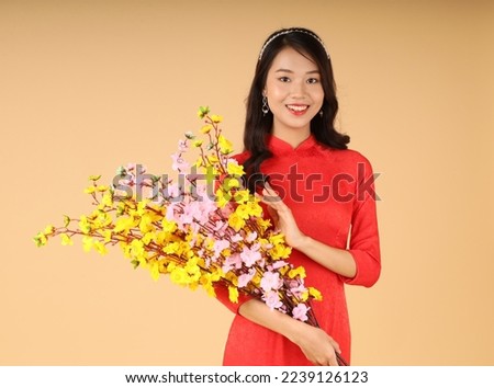 Portrait of a pretty cheerful Vietnamese young lady in traditional outfit, with hand gesture and cute face expression, isolated on the background. Concept of Tet Holiday (Lunar New Year)