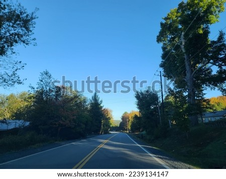 An empty open road running through a rural area on a sunny day.