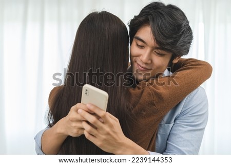 Cheating on girlfriends concept, unfaithful Asian man looking at mobile phone text during embracing with his lover Royalty-Free Stock Photo #2239144353