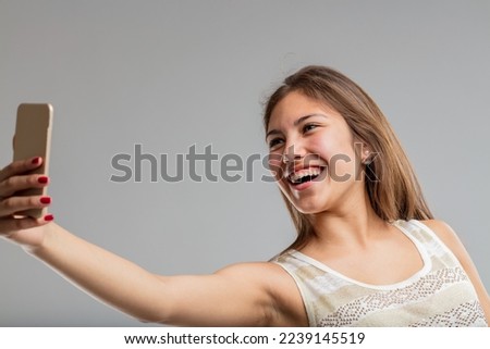 beautiful young woman gleefully watches the screen or takes selfies at the moment in her life when she is more beautiful than she will ever be