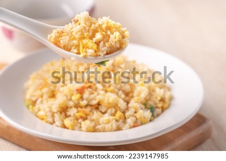 Eating Chinese fried rice with sergestid Sakura shrimp in white plate on bright wooden table background. Royalty-Free Stock Photo #2239147985