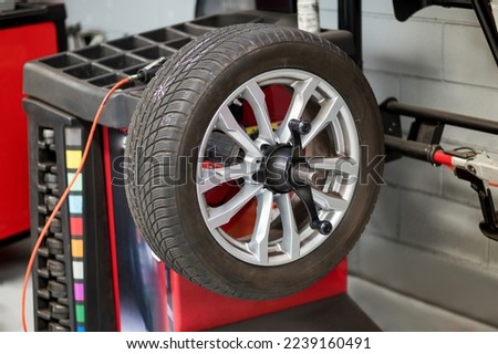 Car wheel balancing on peg attached to rack in workshop of tire dealership