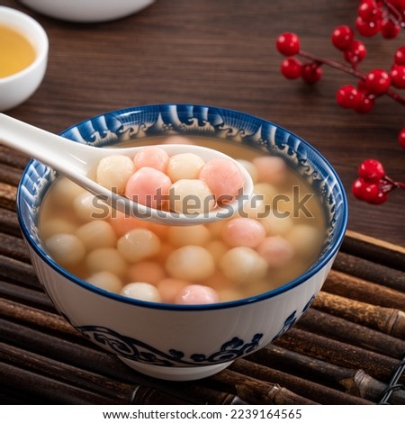 Little red and white tangyuan (tang yuan, rice dumpling balls) with sweet syrup soup for Winter solstice festival on wooden table. Royalty-Free Stock Photo #2239164565