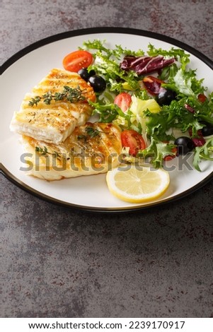 Grilled cod with fresh salad tomatoes, olives, lettuce mix close-up in a plate on the table. Vertical
