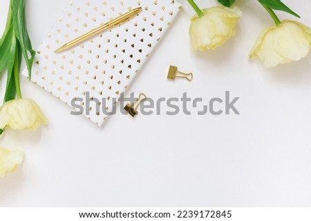 Blogger's spring flat lay. White notepad, pen, bouquet of yellow tulips on a white background with copy space