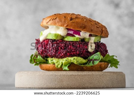 Vegan burger with beetroot cutlet, avocado and vegan mayo sauce on gray background. Healthy veggie food. Close up Royalty-Free Stock Photo #2239206625