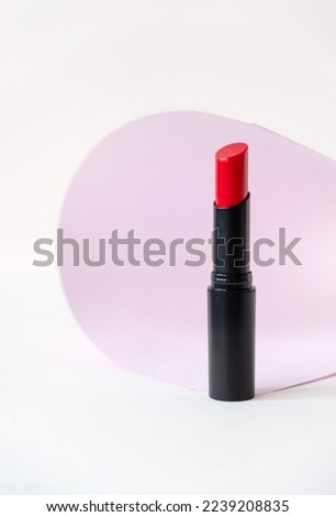 Beautiful red lipstick on white and pink background. Professional makeup product. Lipstick still life on pastel background.