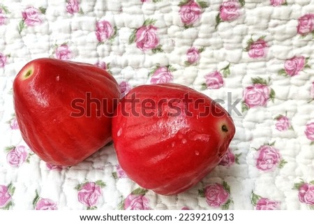 Ripe watery juicy red rose apples or buah jambu air merah in malay on floral background