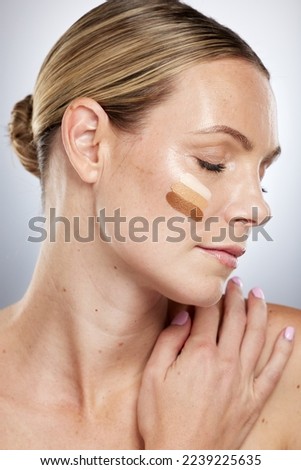 Makeup shade, cosmetics and face of a woman with foundation, facial cream and skincare on a grey studio background. Lotion, bb cream and cosmetic model with swatches of concealer to check for a match Royalty-Free Stock Photo #2239225635