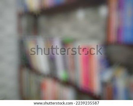 Defocused or blurred abstract background of many colorful books from different genres are put tidily on a wooden dark brown shelf